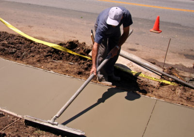 A worker is resurfacing newly installed concrete sidewalk using squeegee