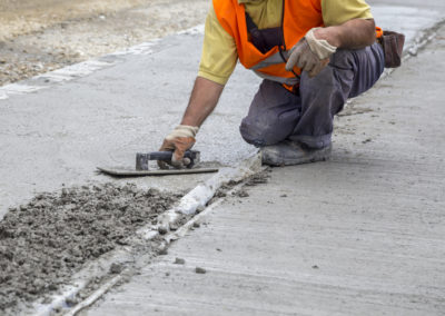 A worker is resurfacing concrete sidewalk using Trowels